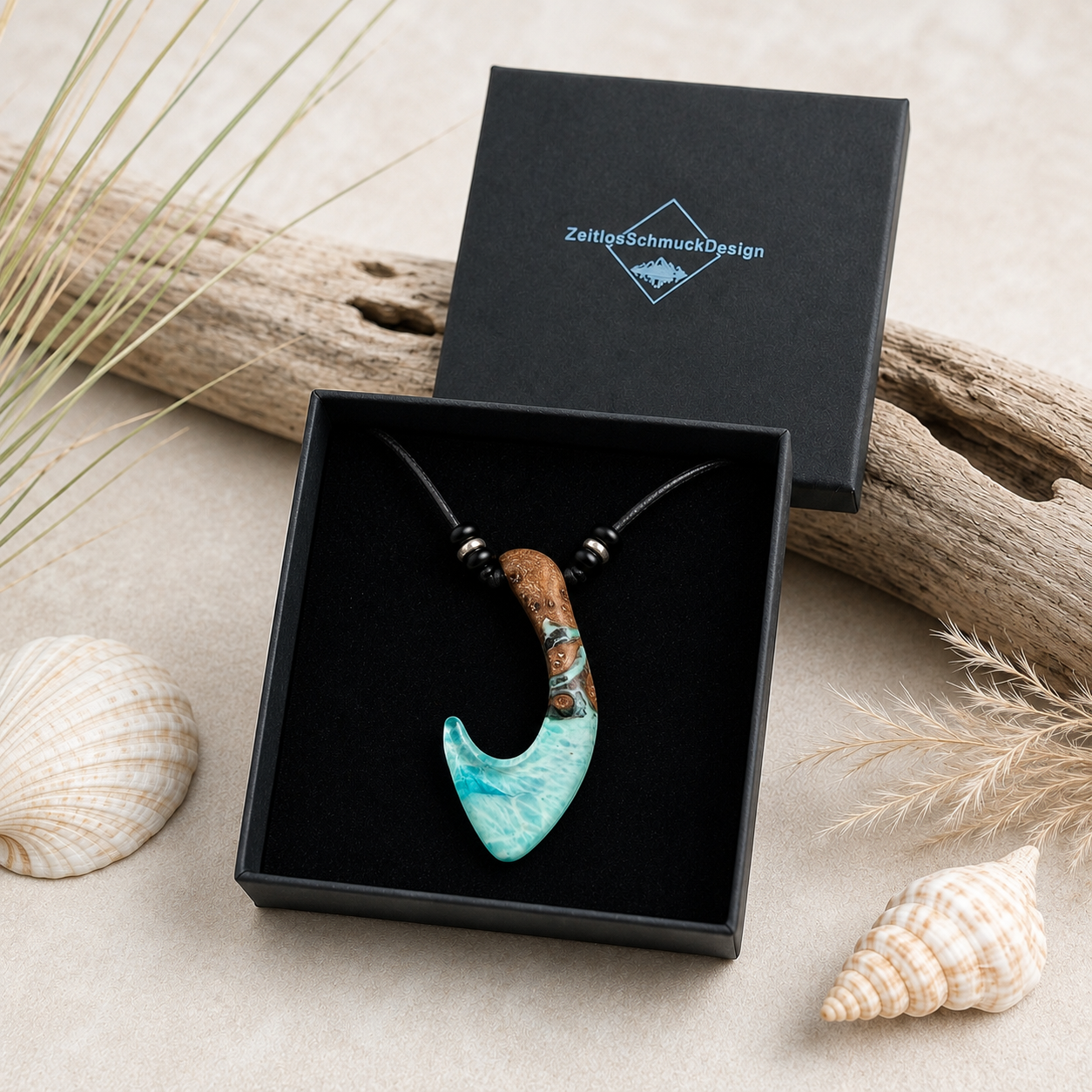 MEERESHAKEN Anhänger aus Maserholz und türkisfarbenem Epoxidharz im Hei-Matau-Stil, präsentiert in der Schmuckbox von ZeitlosSchmuckDesign – handgefertigter maritimer Naturschmuck am schwarzen Lederband mit Onyxperlen und silberfarbenen Spacern.