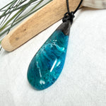Tropfen Anhänger aus dunklem Maserholz und Epoxidharz in Türkis Blau mit weißer Wellenstruktur am schwarzen Lederband, maritimer Holz Harz Naturschmuck