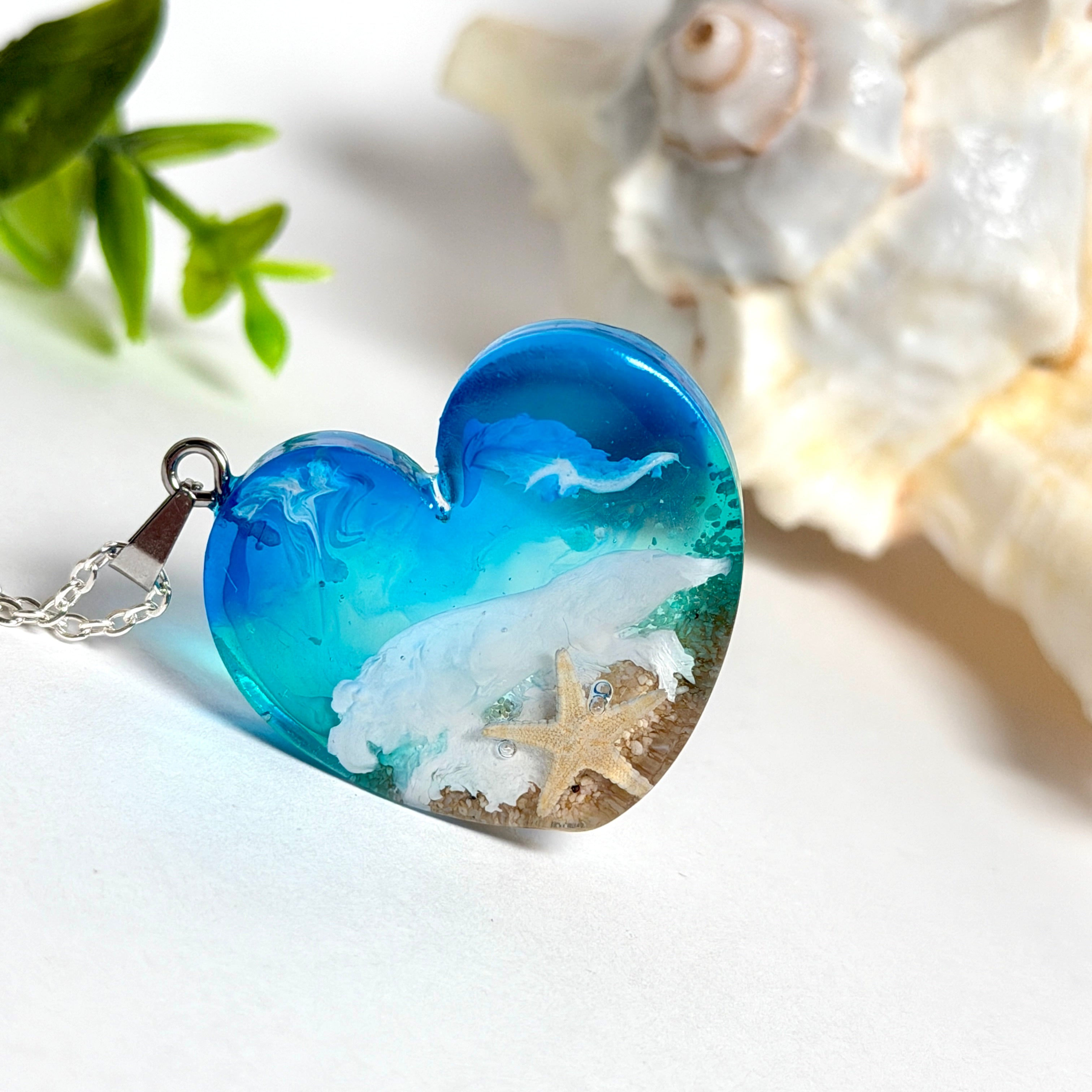 
Ein herzförmiger Anhänger mit einer ganzen Ozeanwelt darin: Welle, Sand und Seestern in leuchtendem Blau und Türkis – handgegossen, einzigartig, unvergesslich. Mit versilberter Kette (46 cm) und Edelstahl-Karabiner.