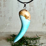 Handgefertigter Anhänger aus Edelholz und transparent-türkisblauem und weißen Epoxidharz, glatt poliert. Größe ca. 6,5 × 2,0 cm. Mit Edelstahlöse an schwarzer Lederkette (45 cm + 5 cm Edelstahl-Verlängerung, Karabiner). Moderner, unisex tragbarer Schmuck mit natürlicher Holzmaserung; kleine Lufteinschlüsse sind charakteristisch.