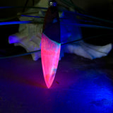 Handgefertigter Surfbrett-Anhänger aus Nussbaumholz und fluoreszierendem Epoxidharz in Pink, Blau und Weiß. Der Anhänger leuchtet zart bei Schwarzlicht und wird an einem verstellbaren Lederband (25–44 cm) mit Holzperlen getragen. Ein maritimes Unikat – ideal für Surfer und Naturliebhaber.