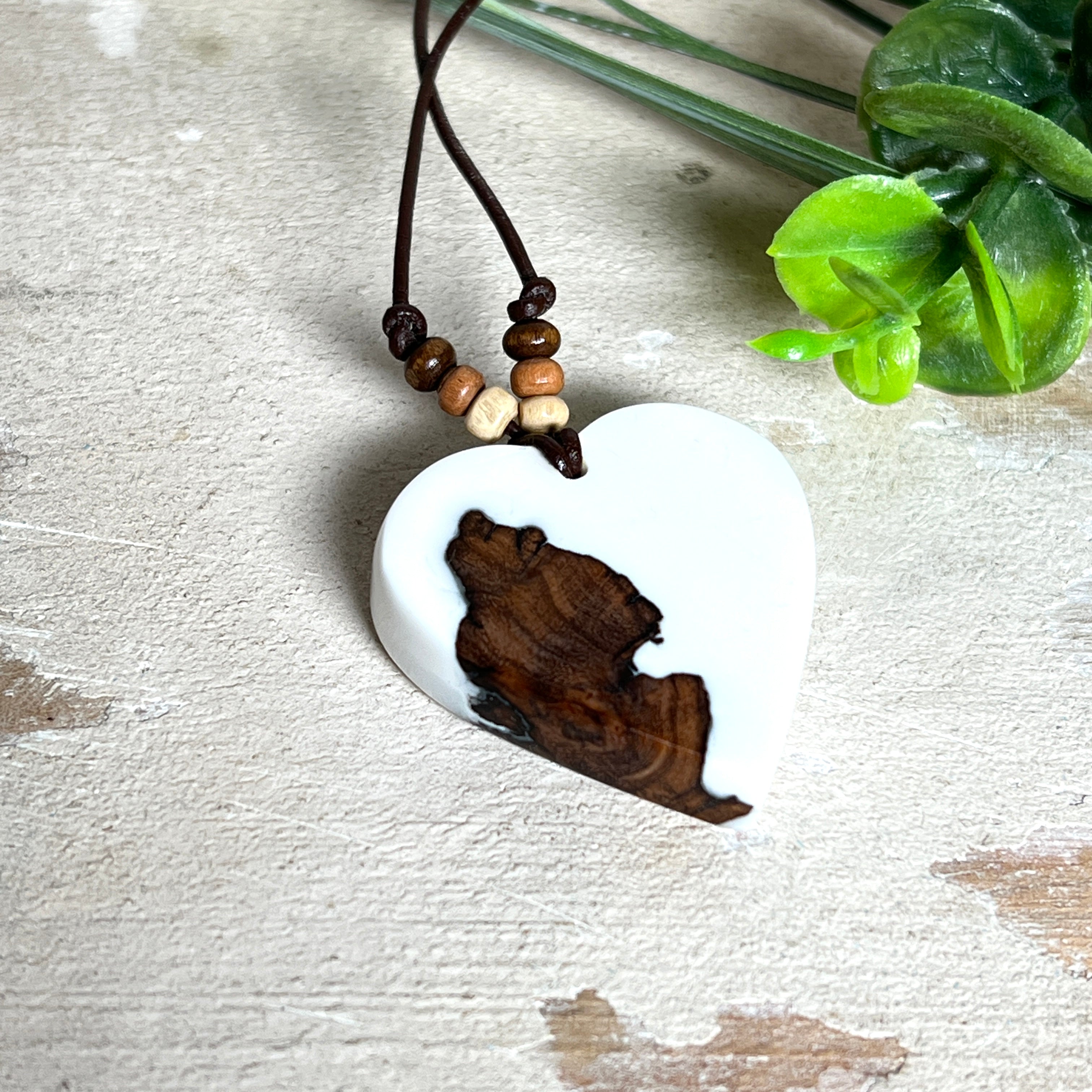 Herzanhänger „Pure Heart“ aus Maserholz und weißem Epoxidharz. Handgefertigtes Unikat mit kontrastreichem Design – die natürliche Maserung des Holzes trifft auf die klare Reinheit von Weiß. Größe ca. 3,5 × 3,5 cm. Verstellbares Lederband (23–41 cm) mit Holzperlen. Ein edles Schmuckstück, inspiriert von Natur und Liebe.