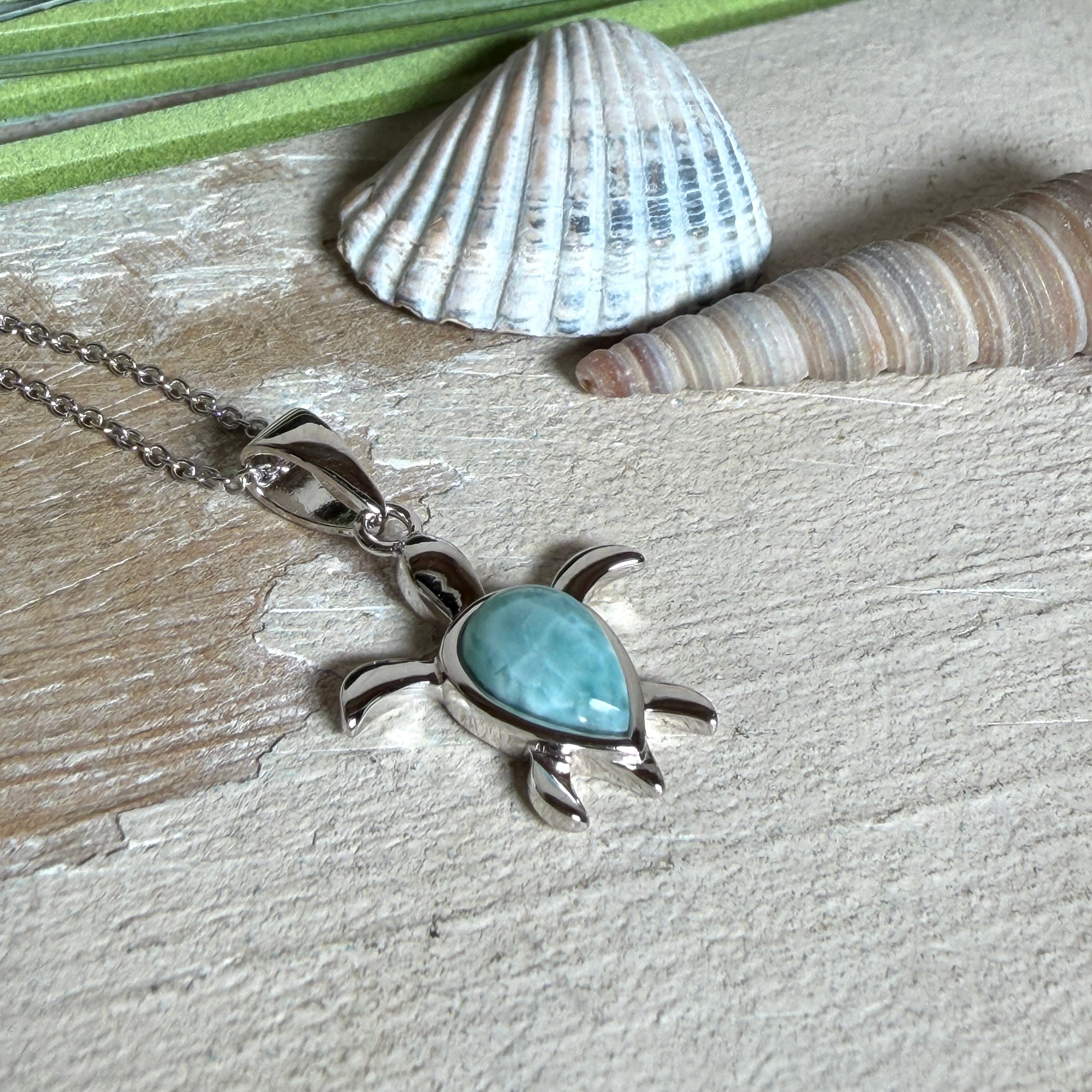 Feine Schildkröten-Kette aus rhodiniertem 925 Silber. Im Panzer des Anhängers liegt ein tropfenförmiger Larimar in hellem Blau. Der Anhänger ist ca. 22 x 18 mm groß und hängt an einer 45 cm langen, 1 mm starken Silberkette.