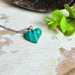 Halskette mit Malachit-Herz: kleiner, gewölbter Herzanhänger aus intensiv grün gebändertem Malachit, ca. 16 x 14 x 10 mm, in hochglanzpolierter, rhodinierter 925 Silberfassung an feiner Ankerkette aus Silber.