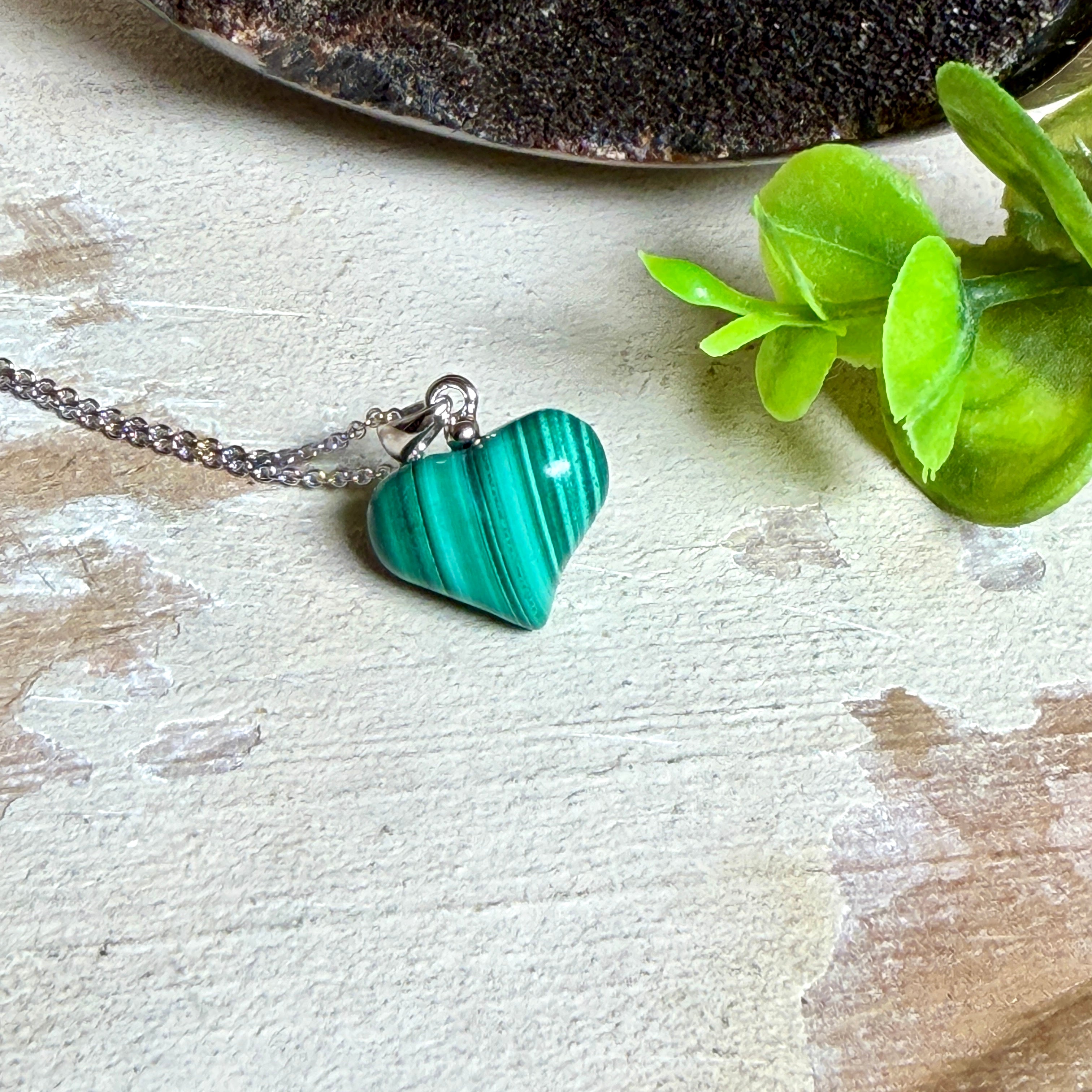Halskette mit Malachit-Herz: kleiner, gewölbter Herzanhänger aus intensiv grün gebändertem Malachit, ca. 16 x 14 x 10 mm, in hochglanzpolierter, rhodinierter 925 Silberfassung an feiner Ankerkette aus Silber.