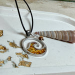 “Runder Wellenanhänger aus Edelstahl mit Bernstein-Harz-Inlay, Jaspisperle & facettiertem Bergkristall an schwarzer Lederkette (45 cm + 5 cm).”