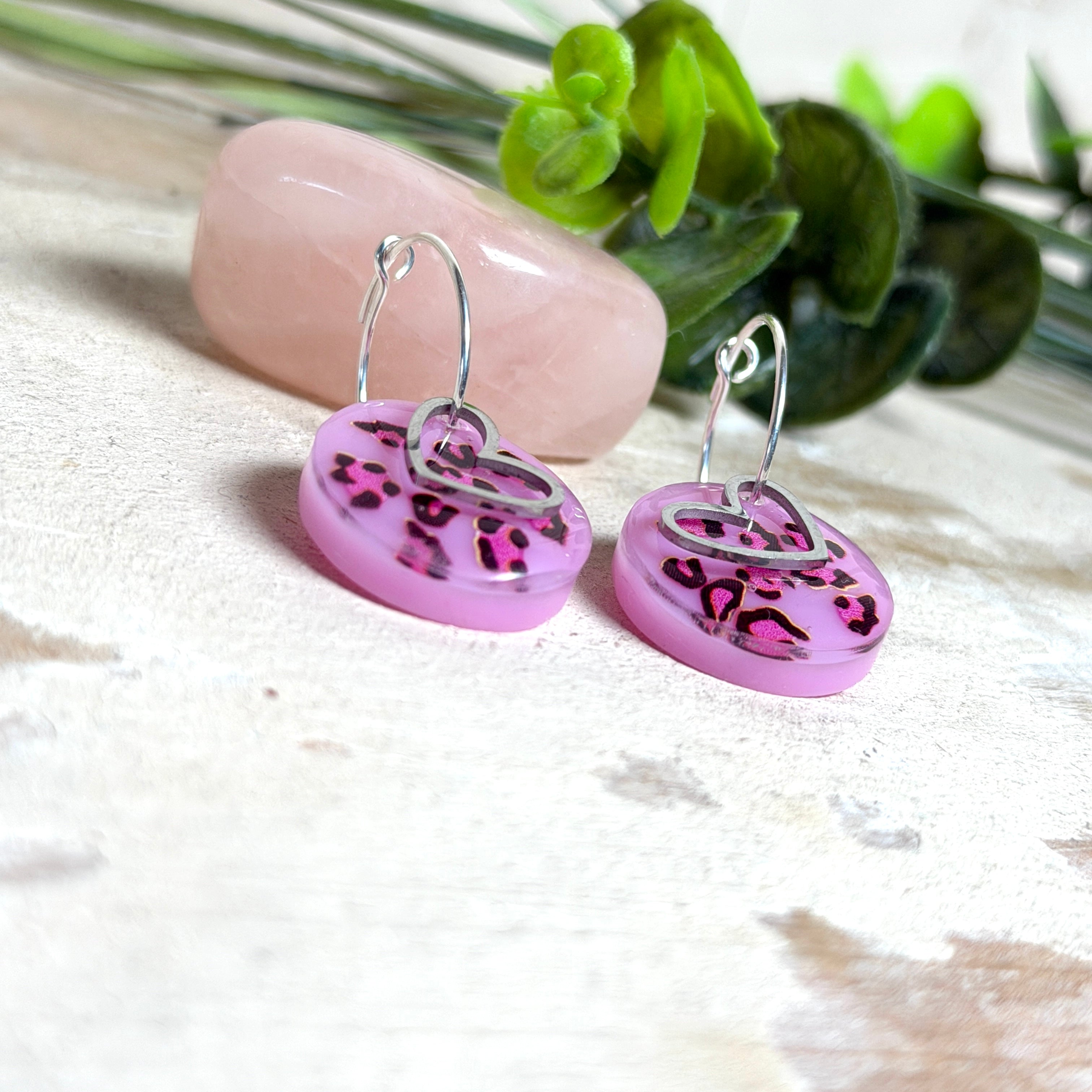 Handgemachte Leo-Creolen aus 925 Silber: Silber-Creolen 16 mm mit rosa Harz-Scheibe (2 cm) im Leoparden-Look und Edelstahl-Herzanhänger. Hängende Ohrringe in Animal-Print Stil, Gesamtlänge ca. 3,5 cm. Resin-Ohrringe für Alltag, Party oder Festival, femininer Statement-Schmuck in Rosa/Pink mit silberfarbenen Metallteilen. Einzeln gegossen, jedes Paar ein Unikat; leichte Abweichungen im Muster, Farbspiel und kleine Luftbläschen sind möglich und typisch für Handarbeit.