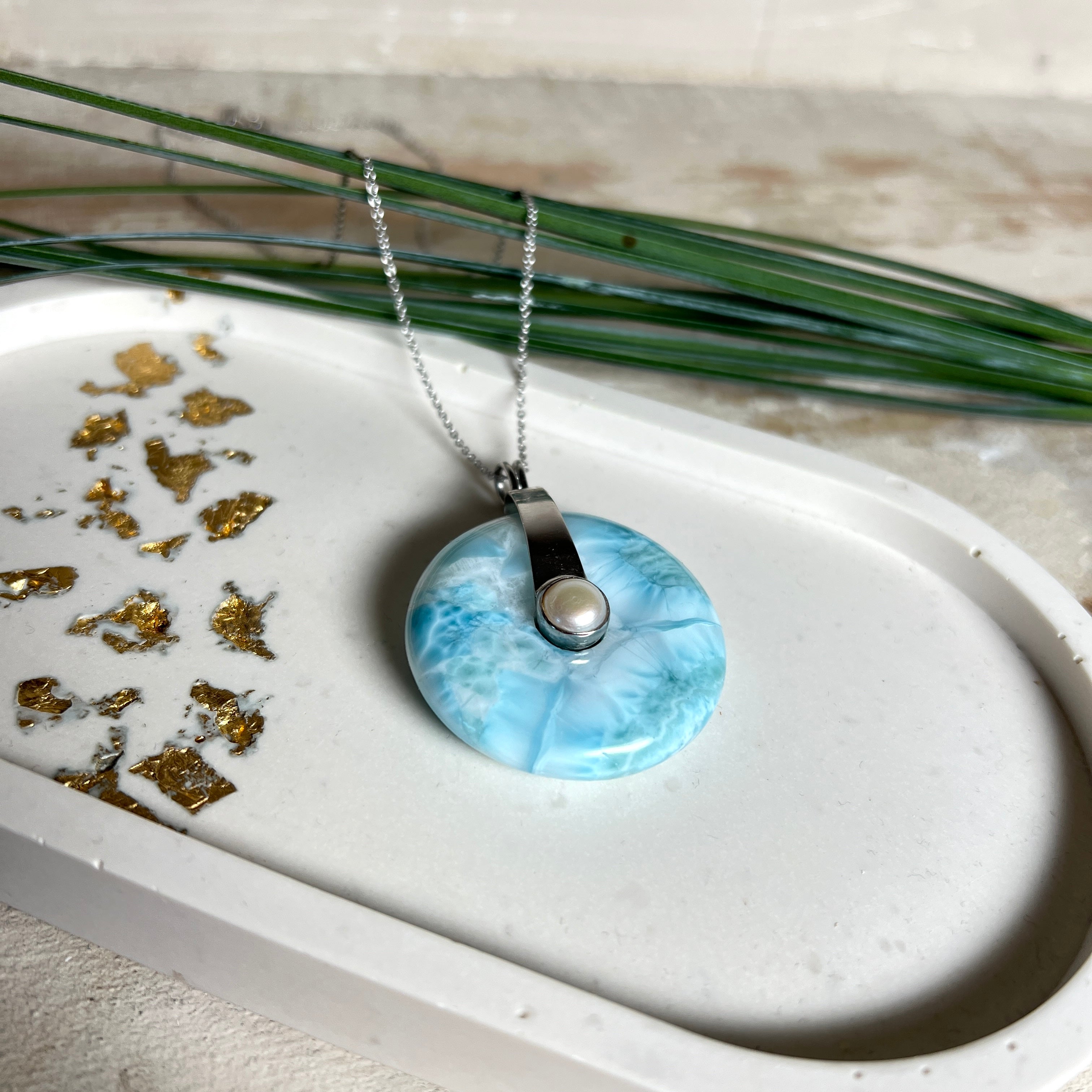 
Echter Larimar-Donut (42 mm) mit Süßwasserperle, gefasst in rhodiniertem 925 Sterlingsilber. Mit 45 cm langer, rhodinierter Silberkette. Selten, edel & handgefertigt – inspiriert vom Blau der Karibik.
