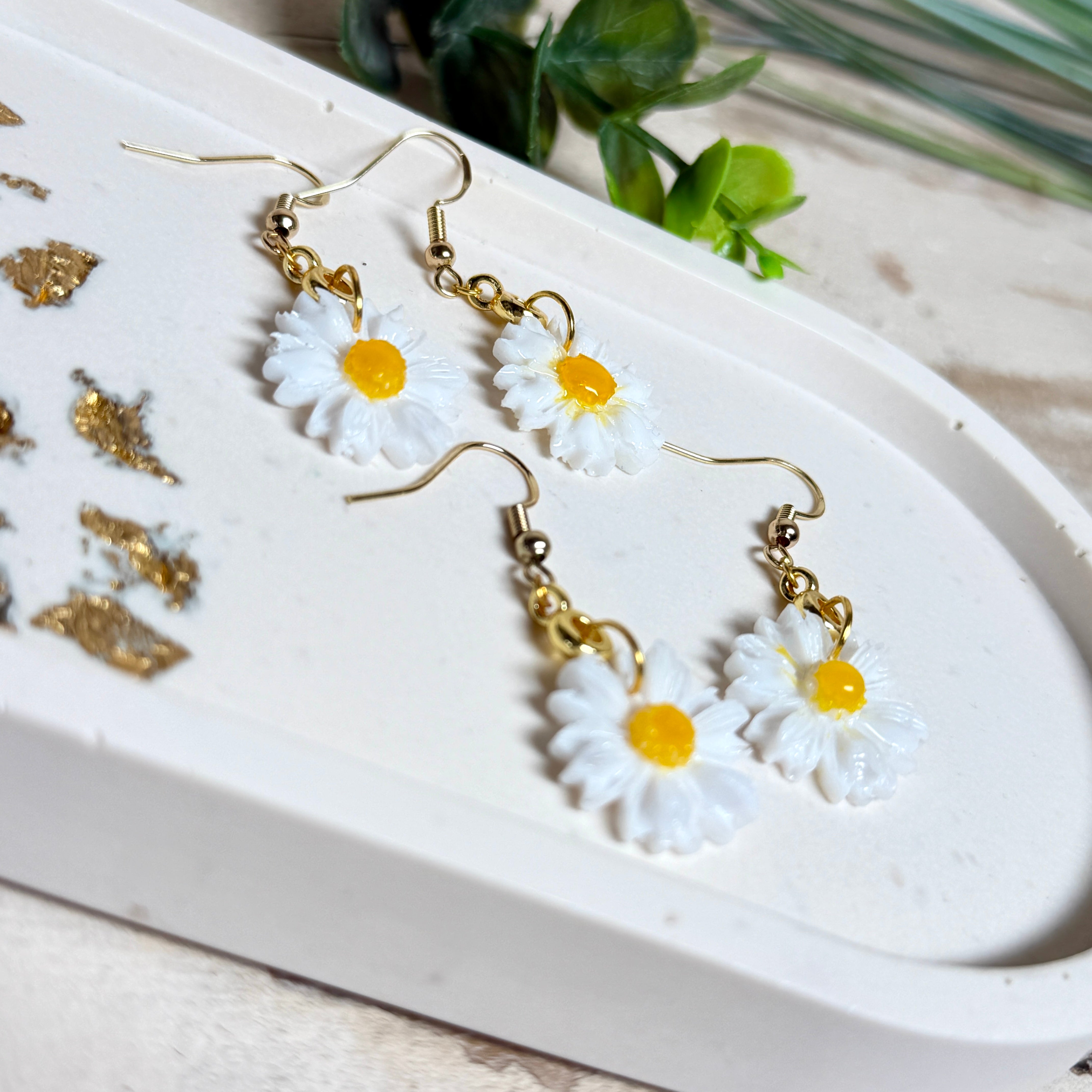 Handgefertigte Gänseblümchen-Ohrringe aus Harz mit 925 vergoldeten Ohrhaken, weiße Blüte mit gelbem Zentrum, goldfarbene Details, Länge ca. 4,5 cm.