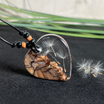 „Handgefertigter Herzanhänger aus Olivenholz und klarem Harz mit echter Pusteblume. Der Anhänger (ca. 3,5 × 3,5 cm) hängt an einem verstellbaren Lederband (23–43 cm) mit Holzperlen. Symbol für Wünsche und Glück, sorgfältig in Handarbeit gegossen, gesägt, geschliffen und poliert. Ein einzigartiger, naturinspirierter Anhänger – ideal als Geschenk oder persönlicher Talisman.“