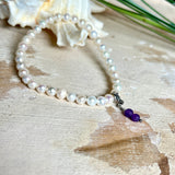 Handgefertigtes Armband „Sea Harmony“ mit schimmernden Süßwasserperlen (Ø ca. 6–7 mm), jede Perle ein Unikat. Auf elastischem Band gefädelt, mit einem filigranen Charmanhänger aus  Amethyst-Perlen, befestigt an einem robusten Edelstahl-Karabiner. Ein Schmuckstück voller Eleganz, maritimer Harmonie und symbolischer Tiefe – ideal als Geschenk oder als stilvolles Accessoire.