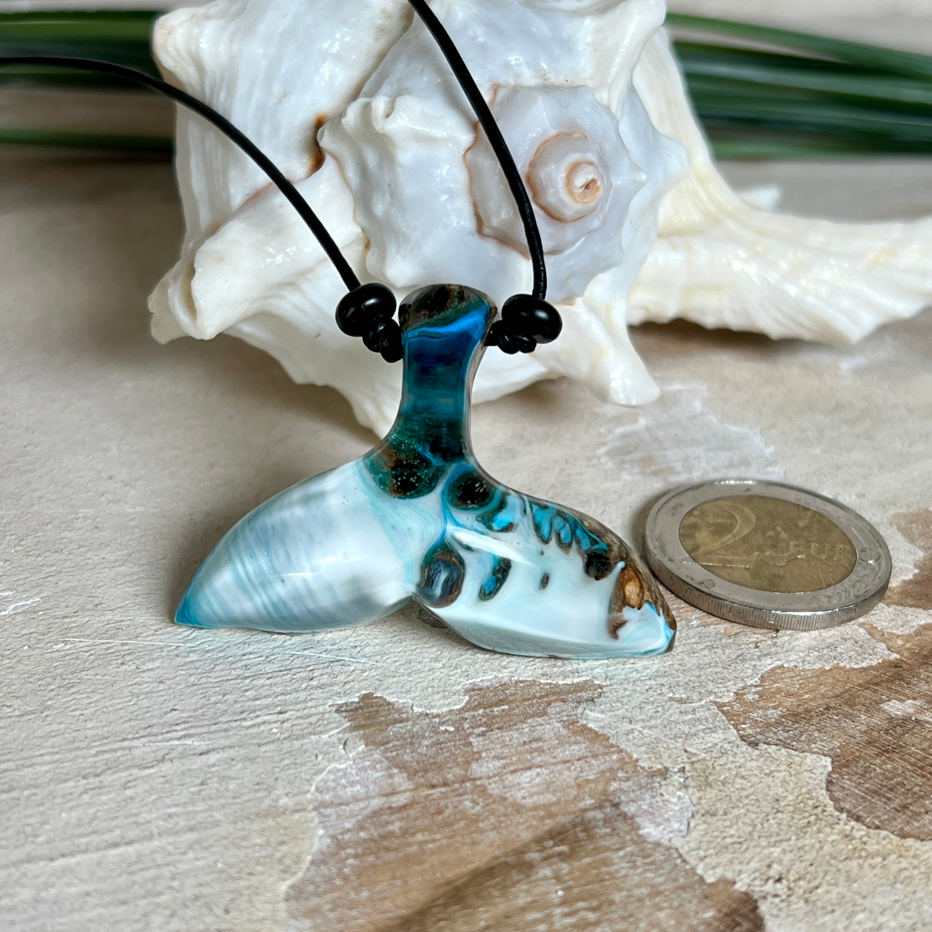 Handgefertigter Walflossen-Anhänger „Flossenklang“ aus Maserholz und türkis-blau-grau-weiß marmoriertem Epoxidharz an verstellbarem Lederband. Maritime Kette als Unikatschmuck für Meeresliebhaber und Wal-Fans, hochwertig poliert, präsentiert vor Muscheldeko und in Schmuckbox von ZeitlosSchmuckDesign.