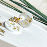 Handgefertigte Ohrringe aus weißem und klarem Harz mit goldenen Weihnachtsmotiven – Sterne, Herzen, Tannenbaum und Zuckerstange. Ohrstecker aus 925 Silber vergoldet, Anhängerschlaufe vergoldet. Größe ca. 37 mm × 25 mm. Leichte, elegante Festtagsohrringe mit warmem Goldglanz und winterlicher Ausstrahlung.