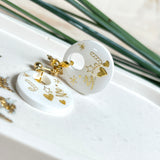 Handgefertigte Ohrringe aus weißem und klarem Harz mit goldenen Weihnachtsmotiven – Sterne, Herzen, Tannenbaum und Zuckerstange. Ohrstecker aus 925 Silber vergoldet, Anhängerschlaufe vergoldet. Größe ca. 37 mm × 25 mm. Leichte, elegante Festtagsohrringe mit warmem Goldglanz und winterlicher Ausstrahlung.