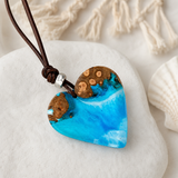 Handgefertigte OZEANHERZ Halskette aus Maserholz und blau-weißem Epoxidharz mit verstellbarem Lederband, silberfarbener Spacer-Perle und Herz Anhänger im maritimen Boho Stil – einzigartiges Schmuck Unikat für Meerliebhaberinnen.