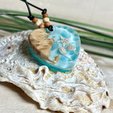 Handgefertigter Herzanhänger aus Maserholz und transparentem Ocean-Harz mit echtem Seestern und Muscheln. Die zarten Aqua-Farben erinnern an Meereswellen. Lederband verstellbar mit Holzperlen. Größe ca. 3,5 × 3,2 cm. Natürliches, maritimes Unikat von ZeitlosSchmuckDesign