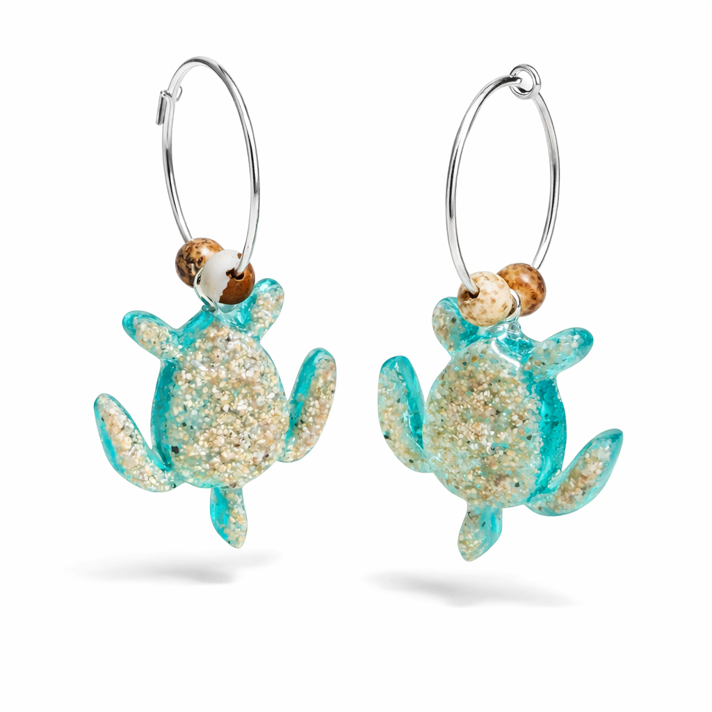 Türkisfarbene Schildkröten-Creolen an feinen 16-mm-Ringen aus 925 Silber, jeweils mit echtem Strandsand im Harz eingebettet und mit kleinen Jaspis-Edelsteinperlen verziert; handgefertigtes Unikat mit sommerlich-maritimem Look, fotografiert als Freisteller, Nahaufnahme oder auf dekorativem Untergrund.