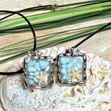 Quadratischer Larimar-Mosaik Anhänger im Edelstahlrahmen mit Seestern-Element und facettierter Bergkristall-Perle, eingebettet in Harz, an schwarzer Lederkette.