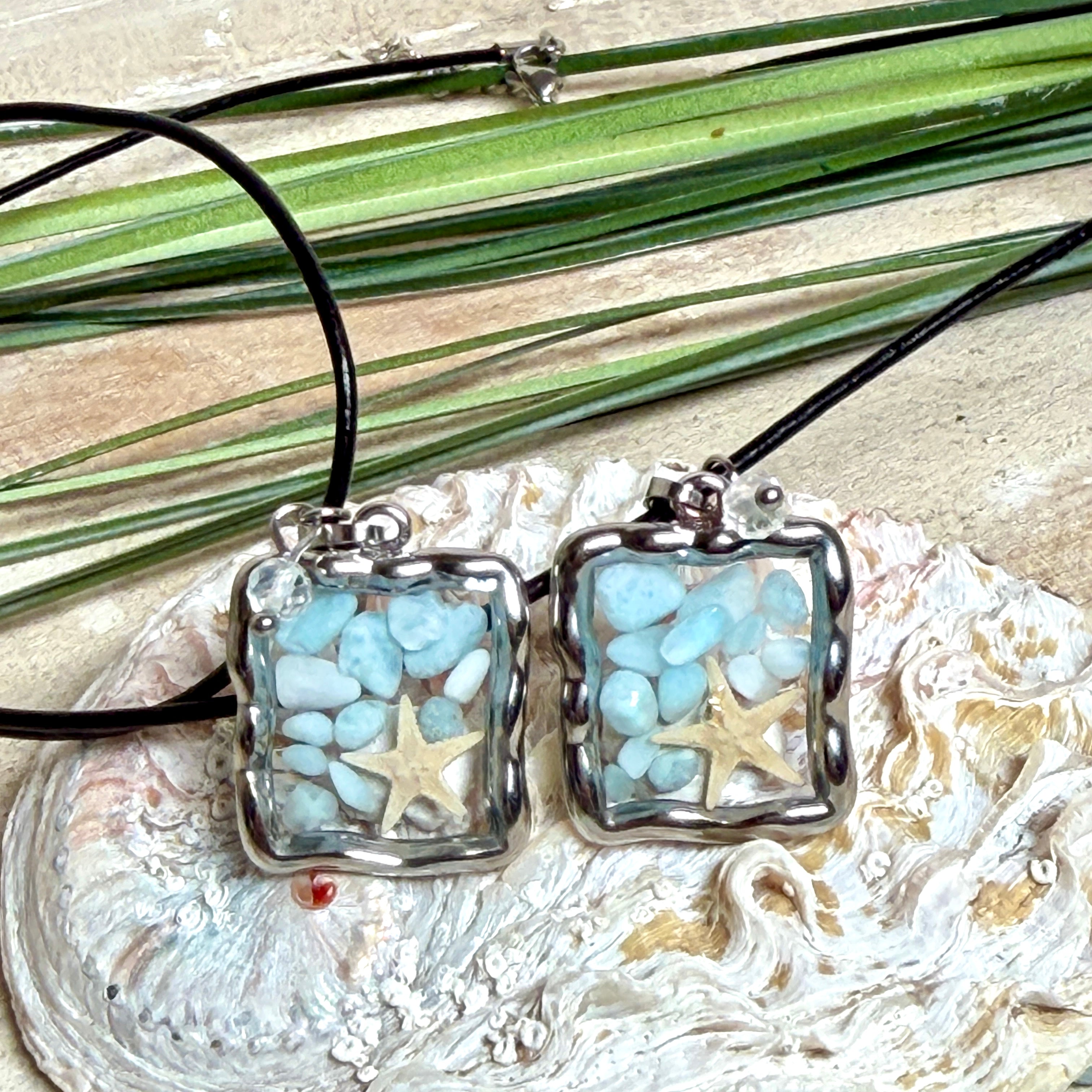 Quadratischer Larimar-Mosaik Anhänger im Edelstahlrahmen mit Seestern-Element und facettierter Bergkristall-Perle, eingebettet in Harz, an schwarzer Lederkette.