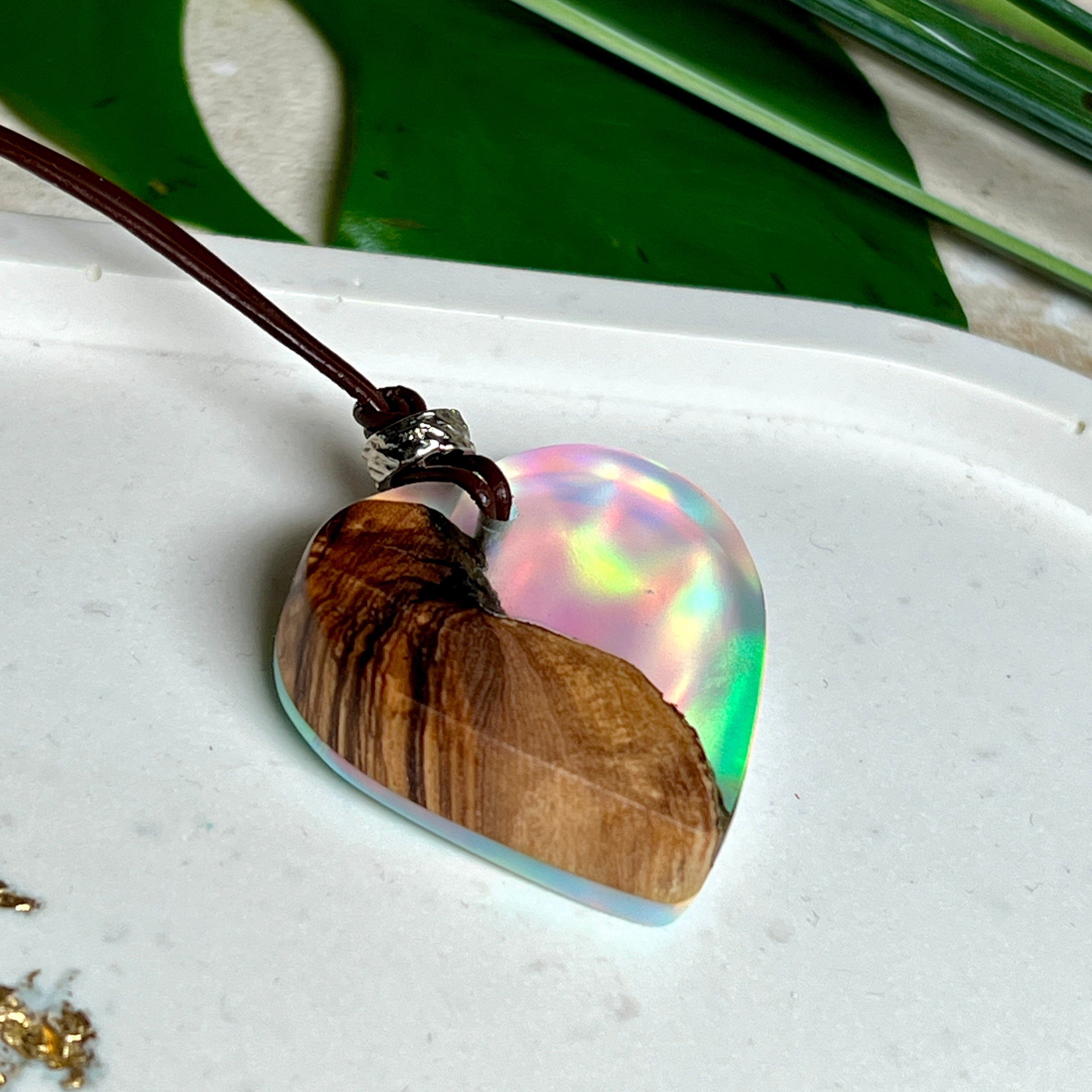 Handgefertigter Herzanhänger aus Olivenholz und schimmerndem Opalharz (Resin Colloidal Imitation Opal) – ein hochwertiges Harz mit feinen, lichtreflektierenden Partikeln, die an echte Opale erinnern. Je nach Licht schimmert der Anhänger in Regenbogenfarben. Mit braunem Lederband und silberfarbener Perle. Jedes Stück ein liebevoll gefertigtes Unikat.