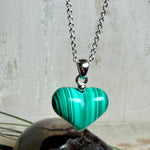 Halskette mit Malachit-Herz: kleiner, gewölbter Herzanhänger aus intensiv grün gebändertem Malachit, ca. 16 x 14 x 10 mm, in hochglanzpolierter, rhodinierter 925 Silberfassung an feiner Ankerkette aus Silber.