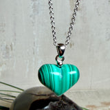 Halskette mit Malachit-Herz: kleiner, gewölbter Herzanhänger aus intensiv grün gebändertem Malachit, ca. 16 x 14 x 10 mm, in hochglanzpolierter, rhodinierter 925 Silberfassung an feiner Ankerkette aus Silber.