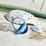 Ovale Halskette „Ocean Crest“ mit 3D-Welle: handgefertigter Harz-Anhänger in Silber-Legierung, Farbverlauf von Tiefblau zu Türkis mit weißer Schaumkrone. Größe ca. 3,9 × 2,3 cm, an einer ca. 56 cm langen versilberten Kette. Glänzende Oberfläche, maritimer Look, Unikat-Handarbeit.