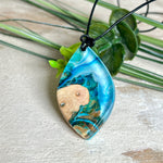 Handgefertigter Anhänger „Ocean Leaf“ aus Maserholz und Epoxidharz in Blau- und Türkistönen. Ein einzigartiges Schmuckstück, das die Schönheit von Natur und Meer einfängt. Mit verstellbarem Lederband (24–43 cm). Jeder Anhänger ist ein Unikat mit einzigartiger Maserung und Farbverlauf.