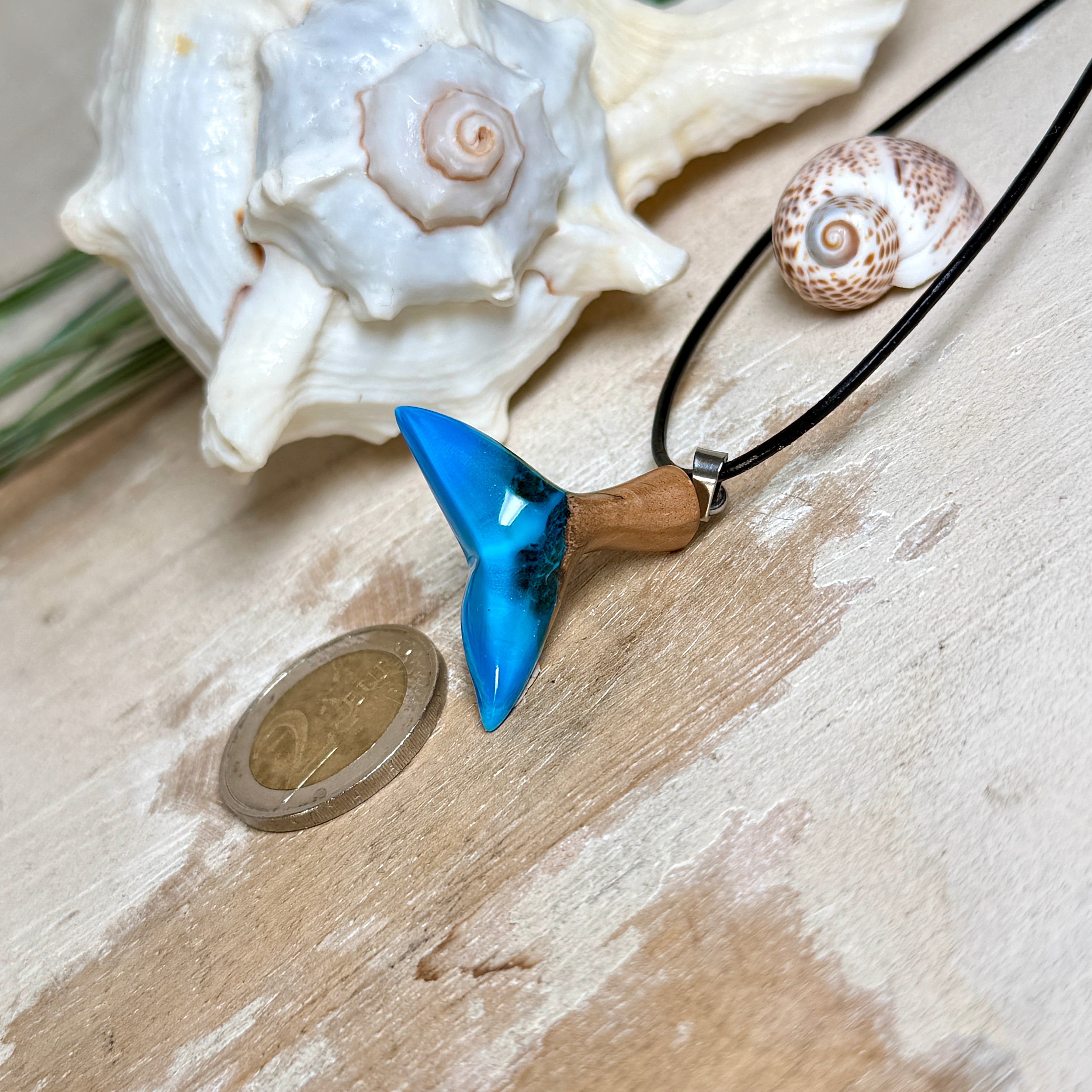 Handgefertigter Walflossen-Anhänger aus Olivenholz und Epoxidharz in Blau-Grün-Weiß, polierte Oberfläche, Edelstahl-Öse. Schwarze Lederkette 45 cm mit Edelstahl-Karabinerverschluss und 5 cm Edelstahl-Verlängerung. Anhängergröße ca. 2,5 × 3,2 cm, maritime Produktfotografie.