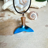 Handgefertigter Walflossen-Anhänger aus Olivenholz und Epoxidharz in Blau-Grün-Weiß, polierte Oberfläche, Edelstahl-Öse. Schwarze Lederkette 45 cm mit Edelstahl-Karabinerverschluss und 5 cm Edelstahl-Verlängerung. Anhängergröße ca. 2,5 × 3,2 cm, maritime Produktfotografie.