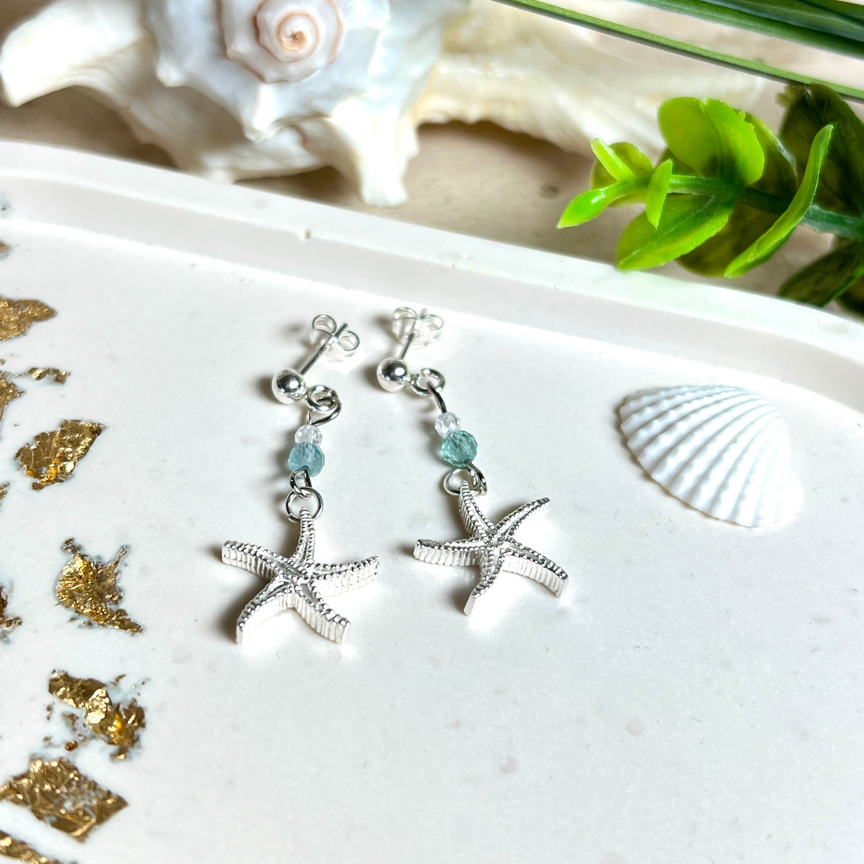 Edle „Ocean Star“ Ohrringe aus 925 Sterling Silber mit Seestern-Anhängern (18 × 17 mm), verziert mit einer aquablauen Apatitperle und funkelndem Zirkonia. Länge getragen: 45 mm. Maritime Schmuckstücke, die das Funkeln des Meeres einfangen – elegant, hochwertig und ein ideales Geschenk für Meeresliebhaber und Sommerträume.