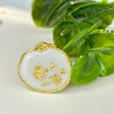 Gold-colored pendant with gold flakes, background in white and fluorescent under black light, birthday, gift