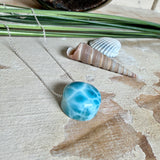 Feine Kette mit rundem Larimar-Cabochon in AA-Qualität. Der ca. 20 mm große Stein zeigt ein intensives Blau mit hellen, netzartigen Zeichnungen und ist mittig mit einer 2,5 mm Bohrung versehen, durch die eine zarte 925 Silberkette (45 cm, ca. 1 mm stark) geführt wird. 