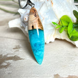 Anhänger aus Eibenholz und Epoxidharz in Blau-Türkis, Weiß und Transparent. Größe ca. 5,8 × 2 cm, Edelstahlöse, Lederkette 45+5 cm. Handgefertigtes Unikat inspiriert vom Ozean.