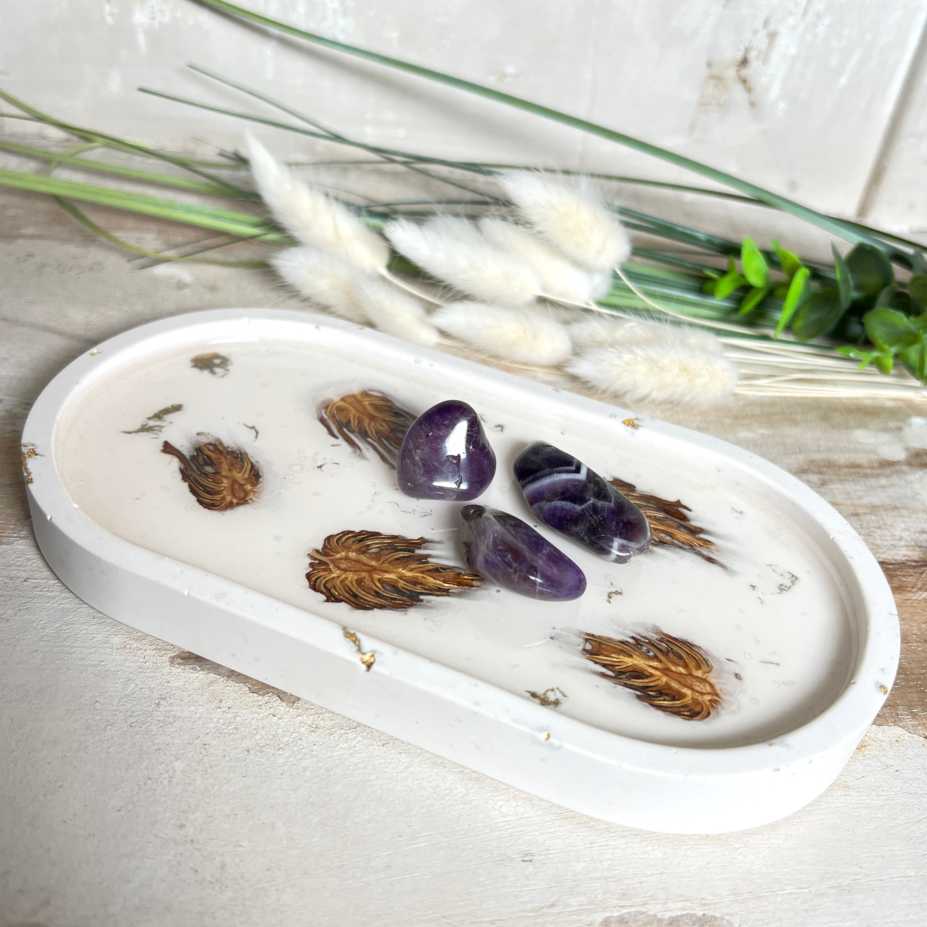 Handgefertigtes Schmucktablett aus Jesmonite mit echten Zapfen, die in einer glänzenden Resin-Schicht eingebettet sind. Die ovale Form und die natürliche Farbgebung machen es zu einem stilvollen Wohnaccessoire. Mit rutschfesten Korkpunkten auf der Unterseite ideal als Ablage für Schmuck, Schlüssel oder Dekoartikel. Jeder Artikel ist ein Unikat aus Handarbeit – Lieferung ohne Dekoration.
