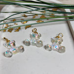 Kleiner Bärchen-Anhänger aus transparentem Harz mit irisierenden Flakes in Regenbogen-Schimmer, goldfarbene Anhängerschlaufe aus Edelstahl. Größe ca. 2,2 × 2,1 cm. Handgefertigtes Unikat; Flakes-Anordnung variiert, vereinzelt kleine Luftbläschen möglich.