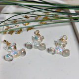 Kleiner Bärchen-Anhänger aus transparentem Harz mit irisierenden Flakes in Regenbogen-Schimmer, goldfarbene Anhängerschlaufe aus Edelstahl. Größe ca. 2,2 × 2,1 cm. Handgefertigtes Unikat; Flakes-Anordnung variiert, vereinzelt kleine Luftbläschen möglich.