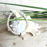 Handgefertigtes Armband „Ocean Bloom“ mit echten, schimmernden Süßwasserperlen (Ø ca. 6–7 mm) auf elastischem Band. Jede Perle ist ein Unikat mit natürlicher Form und sanftem Glanz. Highlight: Charmanhänger mit einer Süßwasserperle und einer facettierten Andenopal-Perle, befestigt an einem robusten Edelstahl-Karabiner. Ein Schmuckstück voller Eleganz, Symbolkraft und maritimer Schönheit.