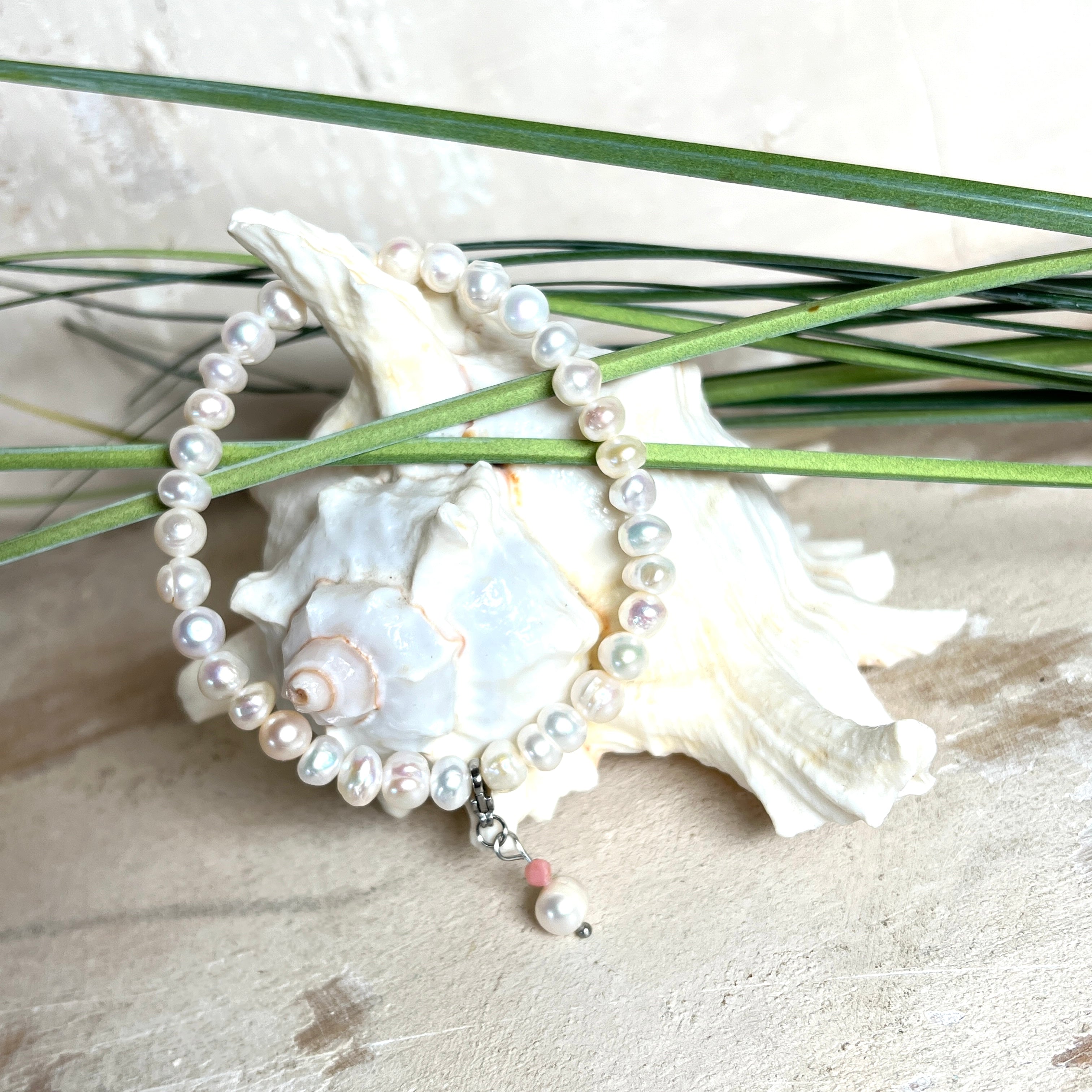 Handgefertigtes Armband „Ocean Bloom“ mit echten, schimmernden Süßwasserperlen (Ø ca. 6–7 mm) auf elastischem Band. Jede Perle ist ein Unikat mit natürlicher Form und sanftem Glanz. Highlight: Charmanhänger mit einer Süßwasserperle und einer facettierten Andenopal-Perle, befestigt an einem robusten Edelstahl-Karabiner. Ein Schmuckstück voller Eleganz, Symbolkraft und maritimer Schönheit.