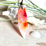 Handgefertigter Surfbrett-Anhänger aus fluoreszierendem Epoxidharz in leuchtenden Orange-, Rot- und Gelbtönen. Leuchtet bei Schwarzlicht. Kombiniert mit verstellbarem Lederband (26–45 cm), verziert mit Spacer- und Holzperlen. Das Design ist inspiriert von der Farbintensität eines Sonnenuntergangs über dem Meer.