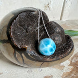 Feine Kette mit rundem Larimar-Cabochon in AA-Qualität. Der ca. 20 mm große Stein zeigt ein intensives Blau mit hellen, netzartigen Zeichnungen und ist mittig mit einer 2,5 mm Bohrung versehen, durch die eine zarte 925 Silberkette (45 cm, ca. 1 mm stark) geführt wird. 