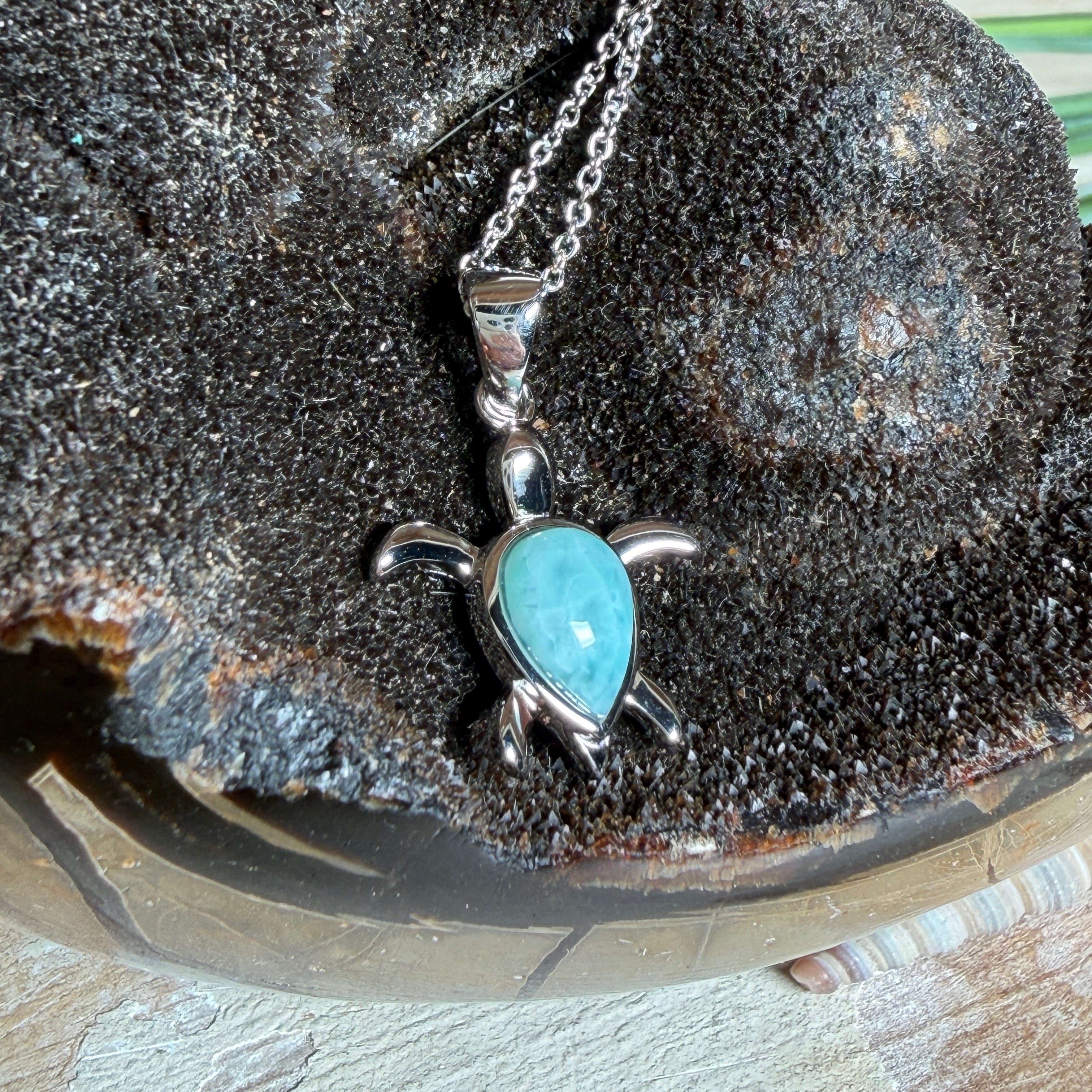 Feine Schildkröten-Kette aus rhodiniertem 925 Silber. Im Panzer des Anhängers liegt ein tropfenförmiger Larimar in hellem Blau. Der Anhänger ist ca. 22 x 18 mm groß und hängt an einer 45 cm langen, 1 mm starken Silberkette.