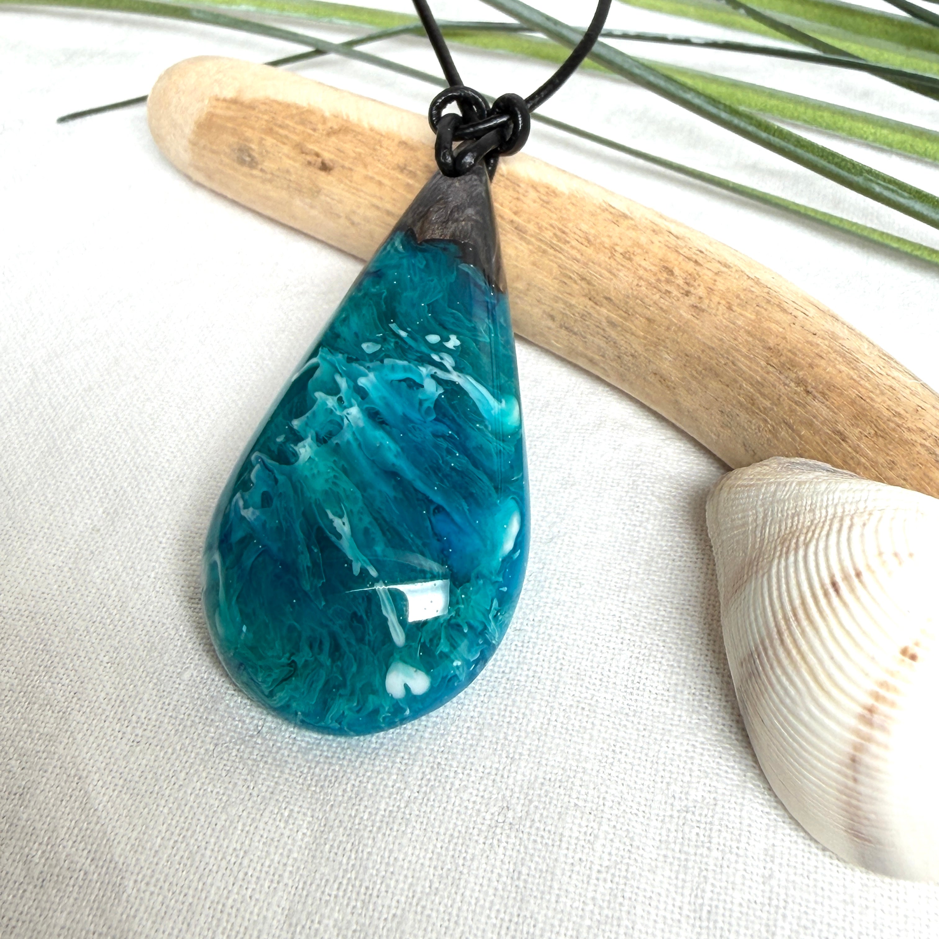 Tropfen Anhänger aus dunklem Maserholz und Epoxidharz in Türkis Blau mit weißer Wellenstruktur am schwarzen Lederband, maritimer Holz Harz Naturschmuck