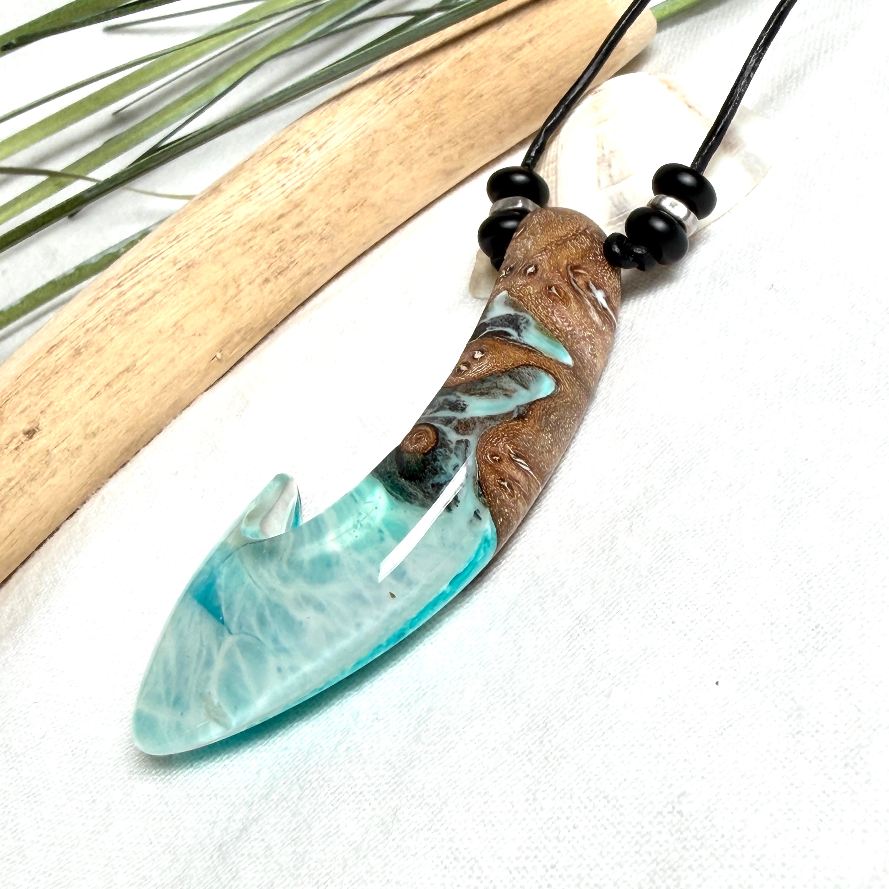 Angelhaken Anhänger aus braunem Maserholz und türkis hellblauem Epoxidharz am schwarzen Lederband mit Onyxperlen, Hei Matau Naturschmuck im Māori Stil