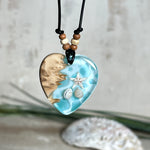 Handgefertigter Herzanhänger aus Maserholz und transparentem Ocean-Harz mit echtem Seestern und Muscheln. Die zarten Aqua-Farben erinnern an Meereswellen. Lederband verstellbar mit Holzperlen. Größe ca. 3,5 × 3,2 cm. Natürliches, maritimes Unikat von ZeitlosSchmuckDesign