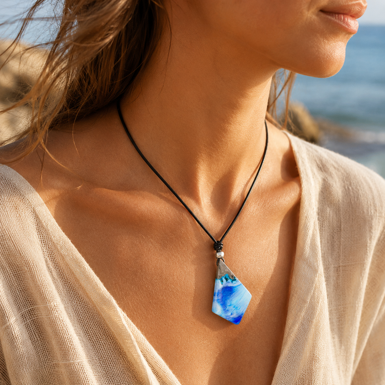 KI-Tragebild WAVE WHISPER – handgefertigter Holz-Harz-Anhänger aus Maserholz und blau-weißem Epoxidharz, maritimer Naturschmuck am schwarzen Lederband, am Hals getragen im sommerlichen Strandlook.