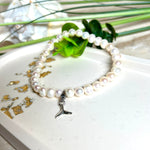 Handgefertigtes Armband aus echten Süßwasserperlen (ca. 6-7 mm), elastisch aufgezogen mit einem Edelstahl-Charm in Form einer Walflosse. Maritimes Design mit Bedeutung – stilvoll, natürlich und elegant. Größe ca. 17,5 cm. Ideal als Geschenk für Meeresliebhaberinnen oder für sich selbst.