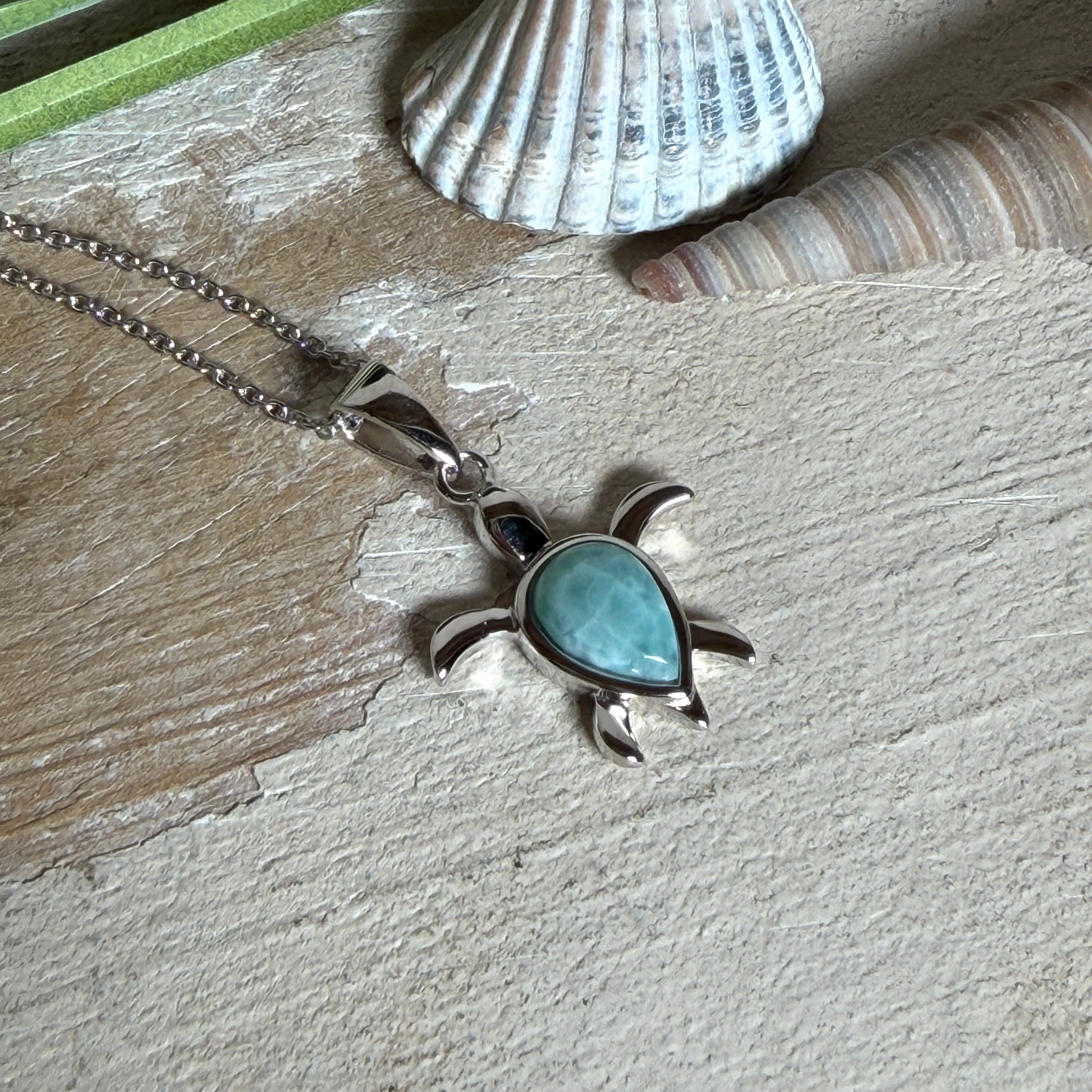 Feine Schildkröten-Kette aus rhodiniertem 925 Silber. Im Panzer des Anhängers liegt ein tropfenförmiger Larimar in hellem Blau. Der Anhänger ist ca. 22 x 18 mm groß und hängt an einer 45 cm langen, 1 mm starken Silberkette.