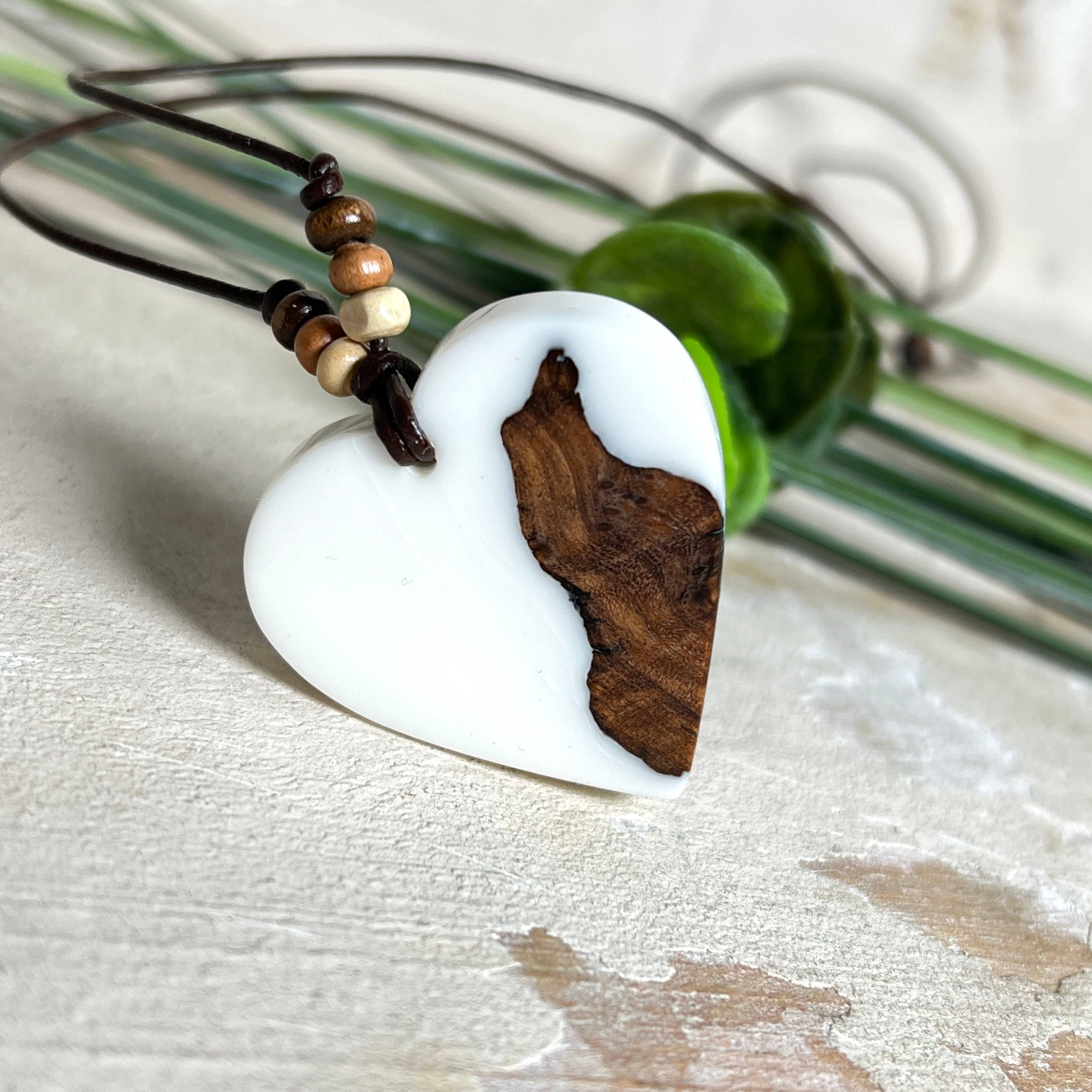 Herzanhänger „Pure Heart“ aus Maserholz und weißem Epoxidharz. Handgefertigtes Unikat mit kontrastreichem Design – die natürliche Maserung des Holzes trifft auf die klare Reinheit von Weiß. Größe ca. 3,5 × 3,5 cm. Verstellbares Lederband (23–41 cm) mit Holzperlen. Ein edles Schmuckstück, inspiriert von Natur und Liebe.