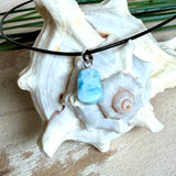 Larimar Freeform Anhänger mit rhodinierter Silberöse an schwarzer Lederkette. Der seltene, kostbare Larimar („Atlantisstein“) zeigt ein lebendiges Muster aus Türkis- und Weißtönen. Beidseitig tragbar, Steingröße ca. 2 x 1 cm, Lederkette 45 cm mit Edelstahl-Karabiner und 5 cm Verlängerung. Natürlicher, maritimer Unikatschmuck.